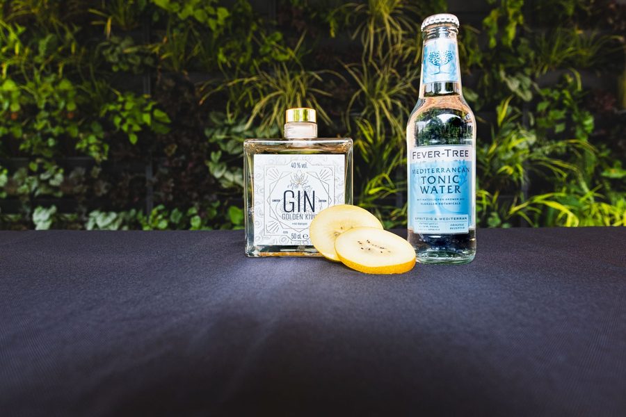 Golden Kiwi Gin mit Tonic und aufgeschnittener gelber Kiwi